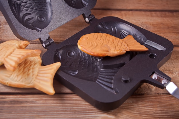 Fisch-förmige süße füllende Waffel des japanischen Straßenlebensmittels Taiyaki auf Holz