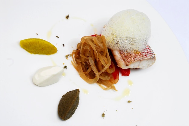 Fisch mit Haut, karamellisierten Zwiebeln und Paprika, bedeckt mit Schaum Nahaufnahme, internationale Küche