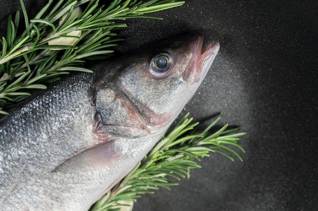 Fisch wird zum Kochen in einer Pfanne mit Rosmarin und Gewürzen zubereitet