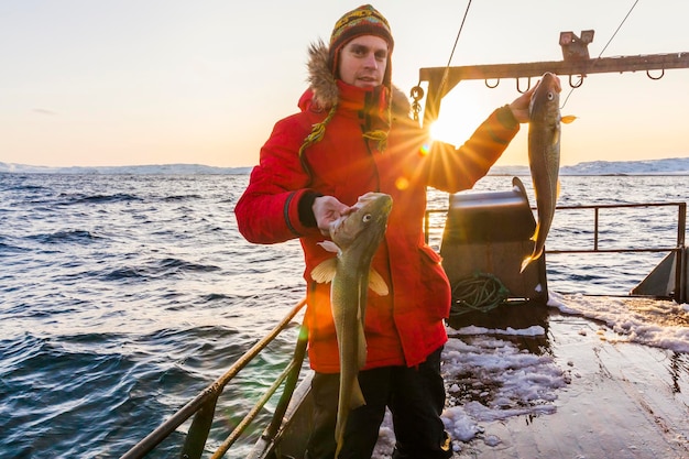 Fischer auf Boot mit Kabeljau in den Händen