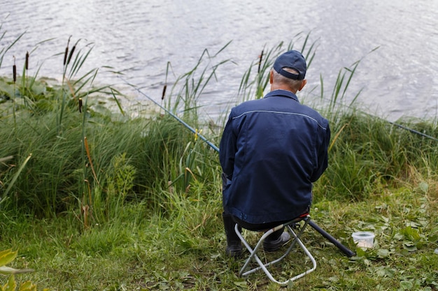 Fischer, der sich mit einer Angelrute am Ufer des Sees zurücklehnt und Fische fängt