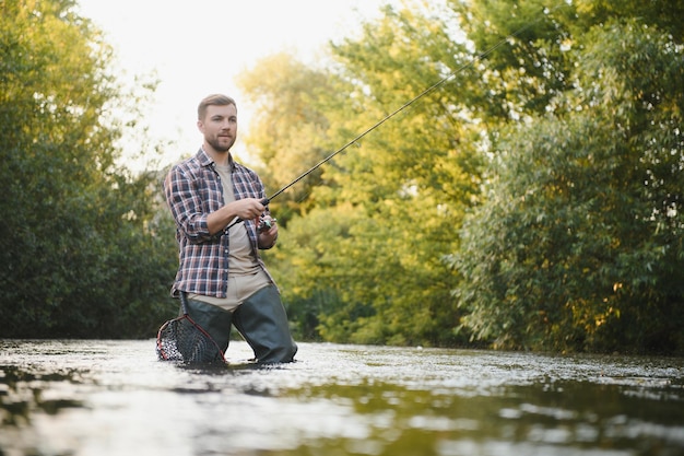 Fischer fängt im Sommer eine Forelle auf dem Fluss