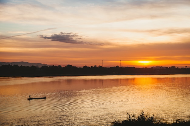 Foto fischer schwimmt auf einem see bei sonnenaufgang.