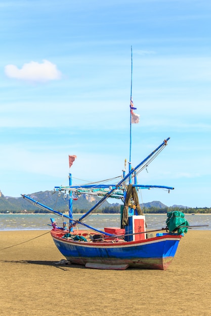 Fischerboot auf Sandstrand und blauem Himmel