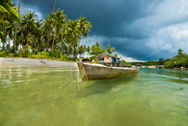 Fischerboot schwimmt über sauberes Wasser am Strand der Insel Bintan