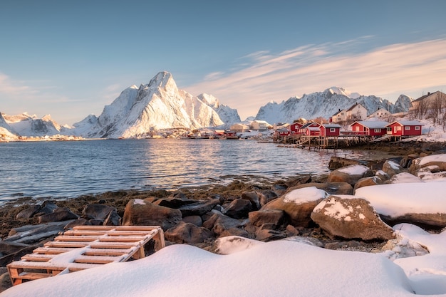 Fischerdorf an der Küste mit Sonnenlicht auf dem Berg im Winter auf den Lofoten-Inseln, Norwegen