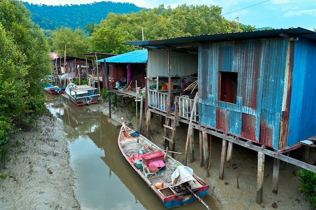 Fischerdorf in Asien. Boote in der Nähe baufälliger Häuser auf Stelzen