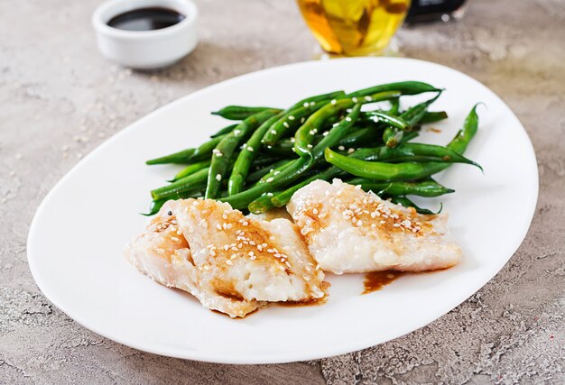 Foto fischfilet diente mit sojasoße und grünen bohnen in der weißen platte. asiatisches essen.