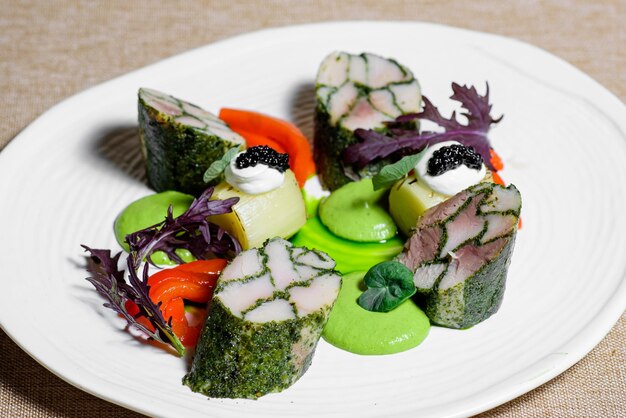 Fischfilet mit rohem Gemüse und Soße in einem weißen Teller auf dem Tisch