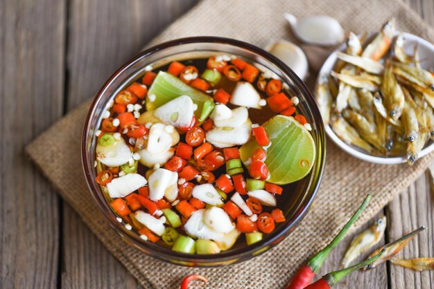 Fischsauce auf weißer Schüssel und frischer Chili Knoblauch Zitrone Limette und kleiner getrockneter Fisch auf Sack Fischsauce, die aus fermentierten Fischen oder kleinen Wassertieren gewonnen wird