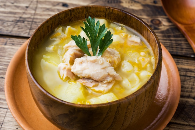 Fischsuppe in einer Holzschale mit frischen Kräutern.