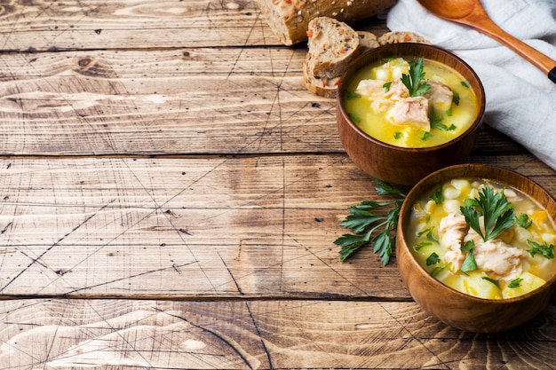 Fischsuppe in einer Holzschale mit frischen Kräutern.