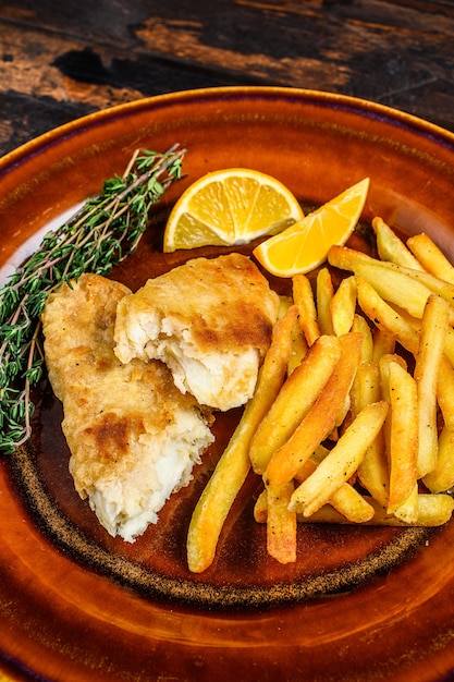 Fish and Chips britisches Fast Food mit Pommes Frites und Tartarsauce auf einem rustikalen Teller