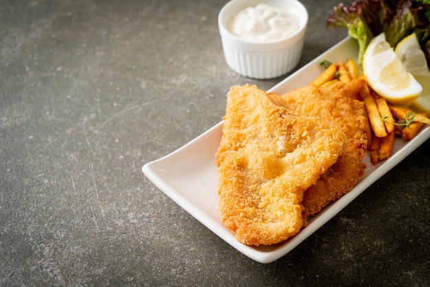 Fish and chips - Filete de pescado frito con patatas fritas y limón en la placa blanca.