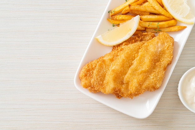 Fish and chips - Filete de pescado frito con patatas fritas y limón en la placa blanca.