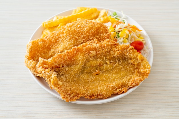 Fish and chips con mini ensalada en la placa blanca.