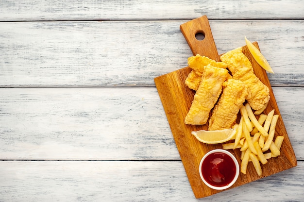 Fish and Chips mit Pommes Frites auf Holzhintergrund