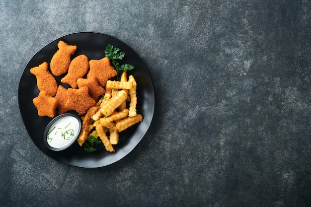 Fish Chips britisches Fast Food Fischstäbchen mit Pommes frites auf schwarzem Teller auf schwarzem Tischhintergrund Traditionelles britisches authentisches Straßenessen oder Essen zum Mitnehmen Mock-up mit Platz für Text