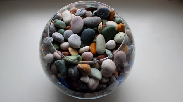 Fishbowl mit farbigen Kieselsteinen und Muscheln auf weißem Hintergrund Winkelansicht stockfoto