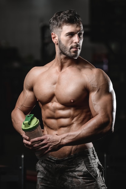 Fisiculturista água potável após o treino. Homem de aptidão muscular esporte cross fitness e musculação conceito ginásio fundo exercícios musculares abs no ginásio conceito de aptidão de tronco nu