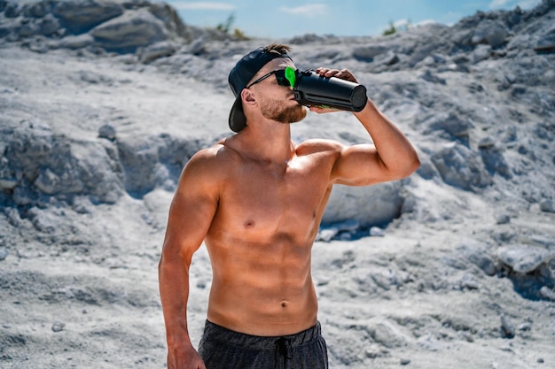 Fisiculturista descansando e bebendo shake de proteína após o exercício Conceito de esporte ao ar livre