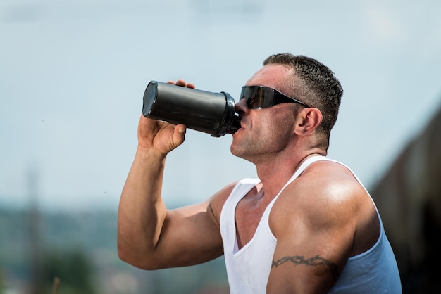 Fisiculturista descansando e bebendo shake de proteína