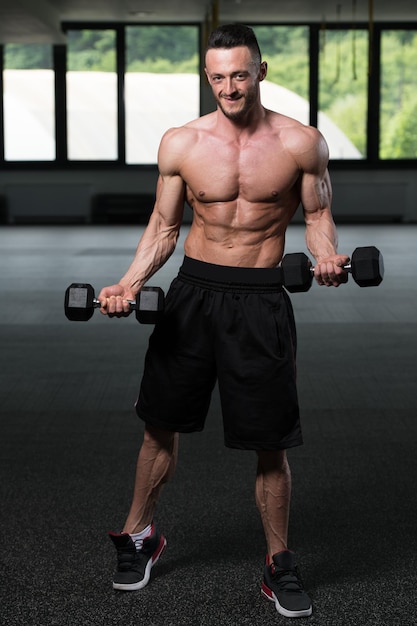 Fisiculturista exercitando bíceps com halteres