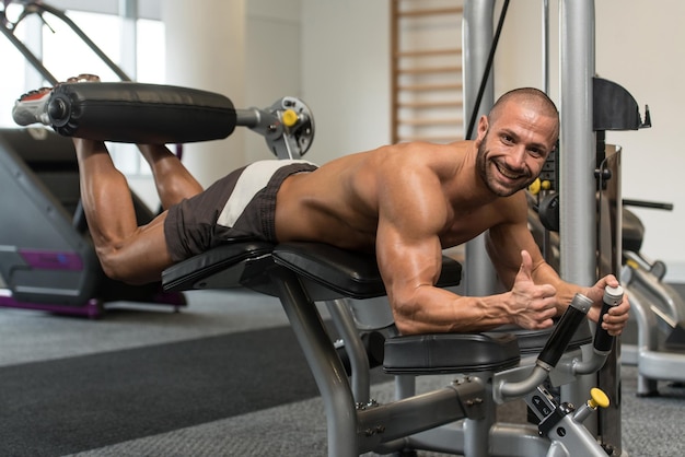 Fisiculturista fazendo exercícios de flexão de pernas na máquina