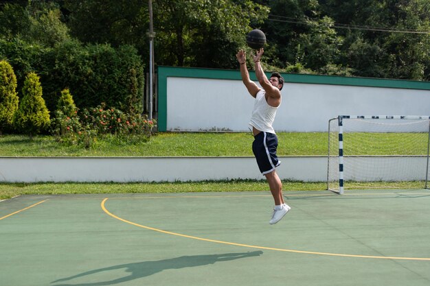 Fisiculturista jogando basquete ao ar livre