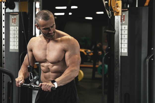 Fisiculturista muscular fazendo flexões de tríceps durante o treino na academia