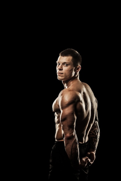 Fisiculturista posando. Poder masculino lindo cara desportivo. Corpo musculoso de aptidão. Isolado em fundo preto