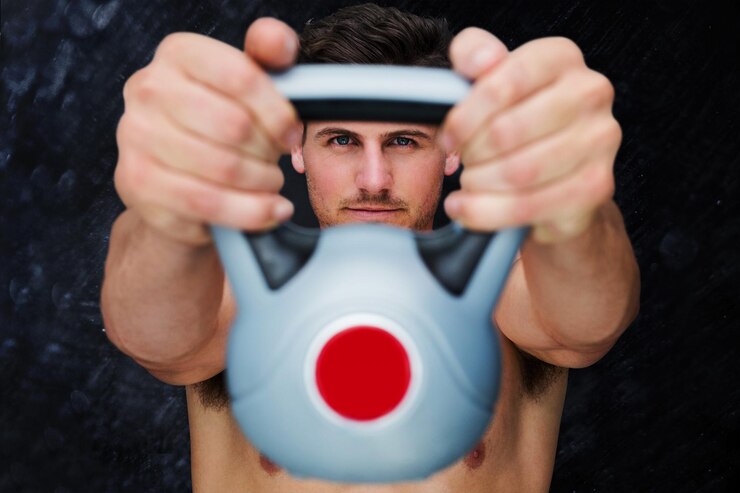 Foto fisiculturista segurando kettlebell contra fundo preto