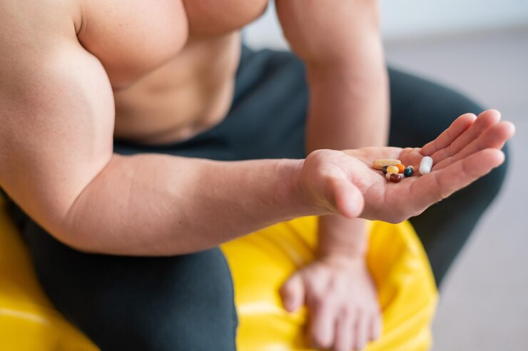 Foto fisiculturista sem rosto bebe cápsulas um close-up de um homem musculoso sem camisa contém um punhado de vitaminas e suplementos de fitness