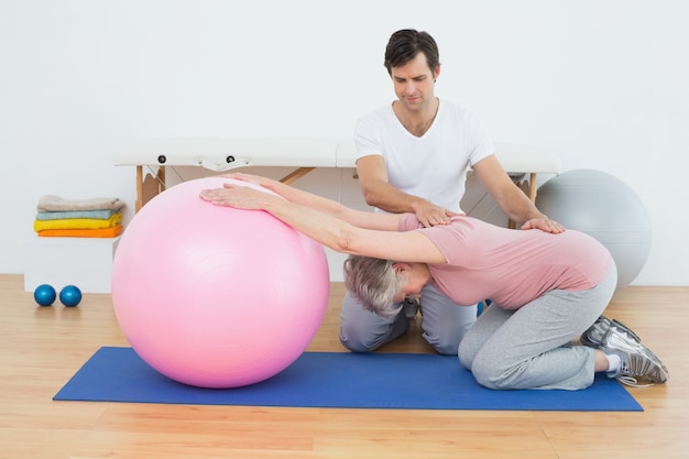 Foto fisioterapeuta, ajudando, mulher sênior, com, ioga, bola