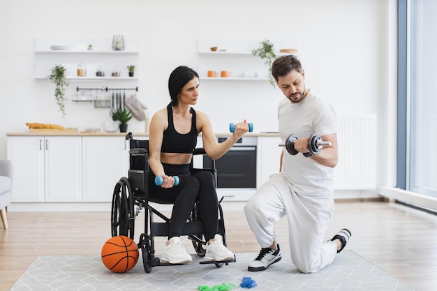 Foto fisioterapeuta ajudando uma mulher adulta em cadeira de rodas a se exercitar com halteres