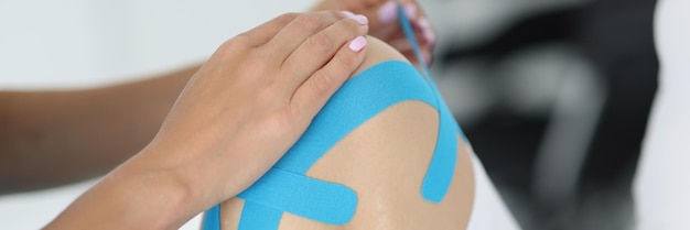 El fisioterapeuta aplica cinta de kinesiología a la rodilla del paciente en la clínica
