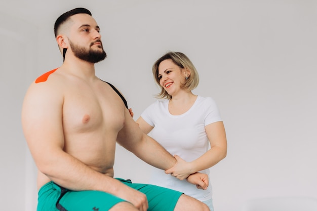 Fisioterapeuta aplicando cinta de Kinesio a pacientes heridos en el hombro