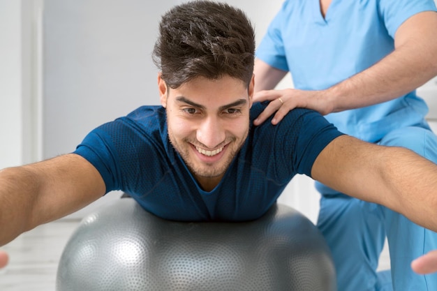 Foto fisioterapeuta ayuda a apuesto joven paciente con ejercicios de pilates