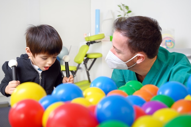 Fisioterapeuta brincando com crianças, com paralisia cerebral.