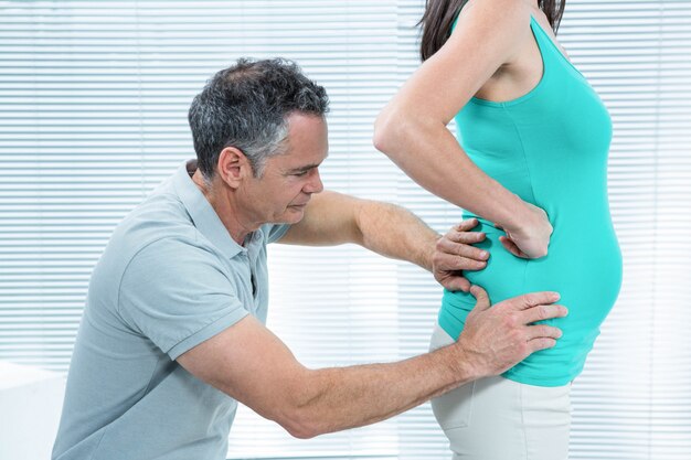 Foto fisioterapeuta comprobando la espalda de la mujer embarazada en la clínica