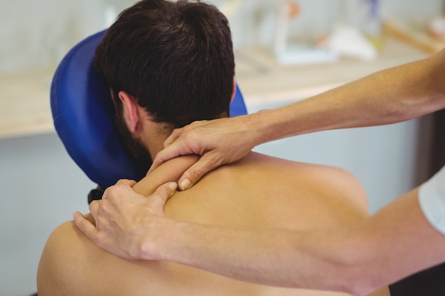 Foto fisioterapeuta dando masaje de espalda a un paciente