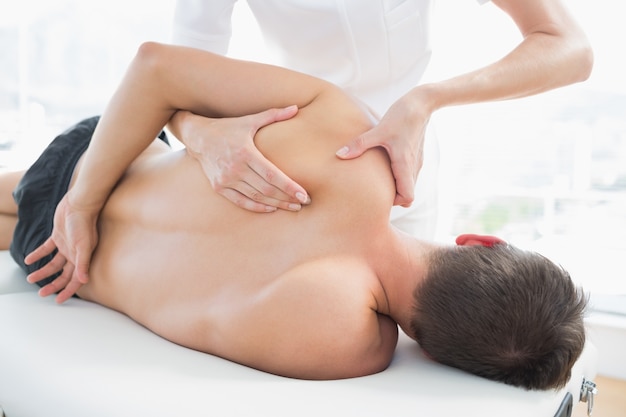 Fisioterapeuta dando masaje de hombro al hombre