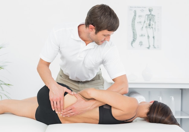 Fisioterapeuta dando masajes a la mujer en consultorio médico