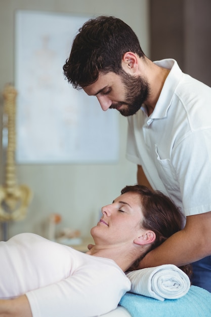 Foto fisioterapeuta dando massagem no pescoço para uma mulher