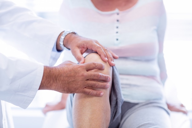 Fisioterapeuta dando terapia de joelho para mulher sênior