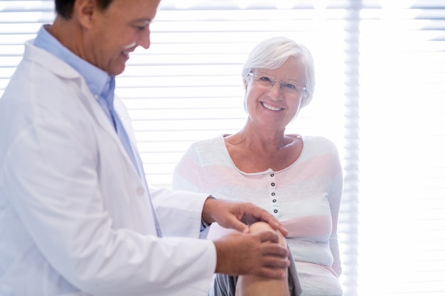 Fisioterapeuta dando terapia de rodilla a mujer senior