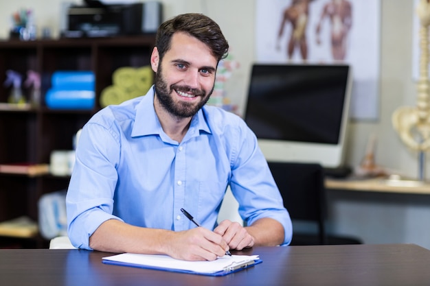 Fisioterapeuta escribiendo en un portapapeles