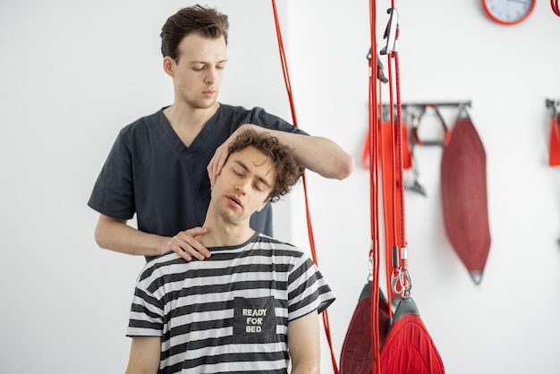 El fisioterapeuta examina al paciente masculino joven en la clínica