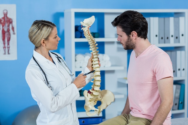 Fisioterapeuta, explicando o modelo da coluna vertebral ao paciente