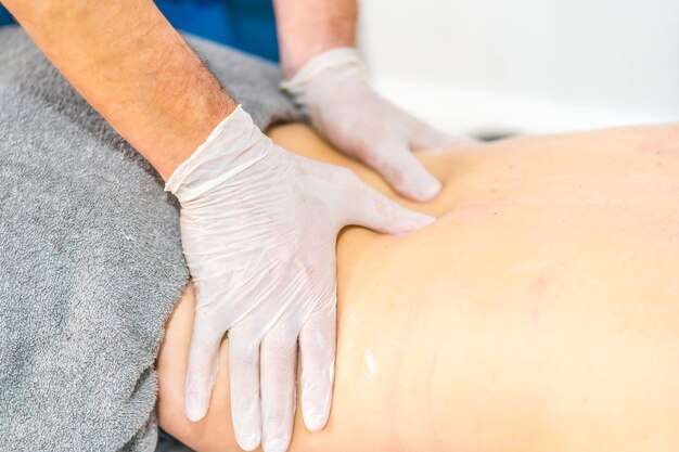 Fisioterapeuta fazendo massagem com luvas Reabertura com medidas de segurança da fisioterapia na pandemia Covid19 Osteopatia quiromassagem terapêutica